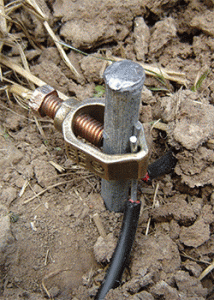 Ground rod installed in the earth with clamp.
