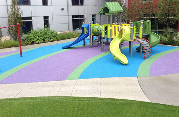 Figure 1: A view of a playground with impact absorbing surfacing. The brightly colored surfacing beneath the play equipment is a poured-in-place rubber and polyurethane material.